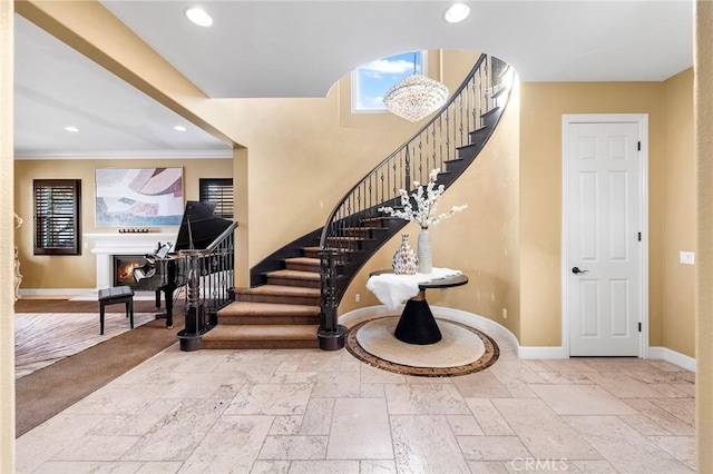 foyer entrance featuring a warm lit fireplace, baseboards, stairway, and stone tile flooring