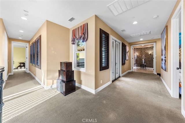 hallway featuring carpet floors, baseboards, and visible vents