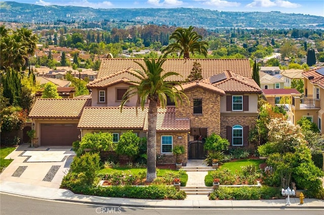 mediterranean / spanish house with driveway, a tile roof, a residential view, stone siding, and stucco siding