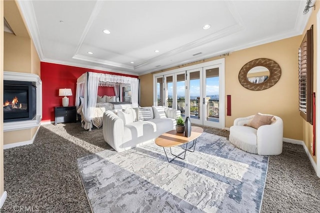 carpeted living room with french doors, a raised ceiling, a glass covered fireplace, and baseboards