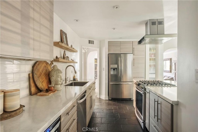 kitchen featuring light countertops, arched walkways, appliances with stainless steel finishes, and a sink