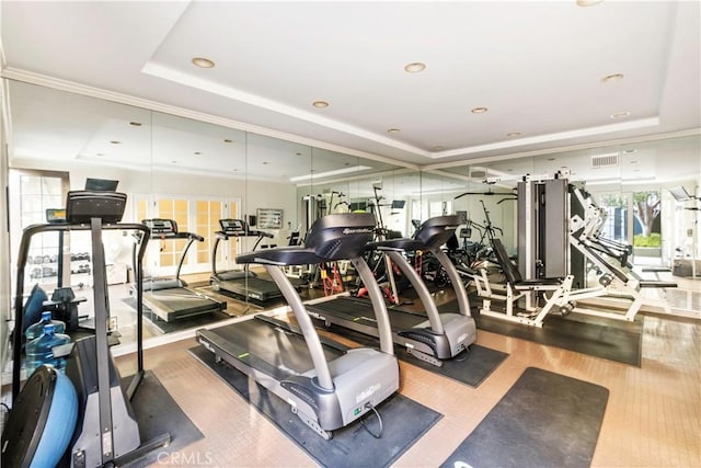 workout area featuring recessed lighting, a tray ceiling, visible vents, and wood finished floors