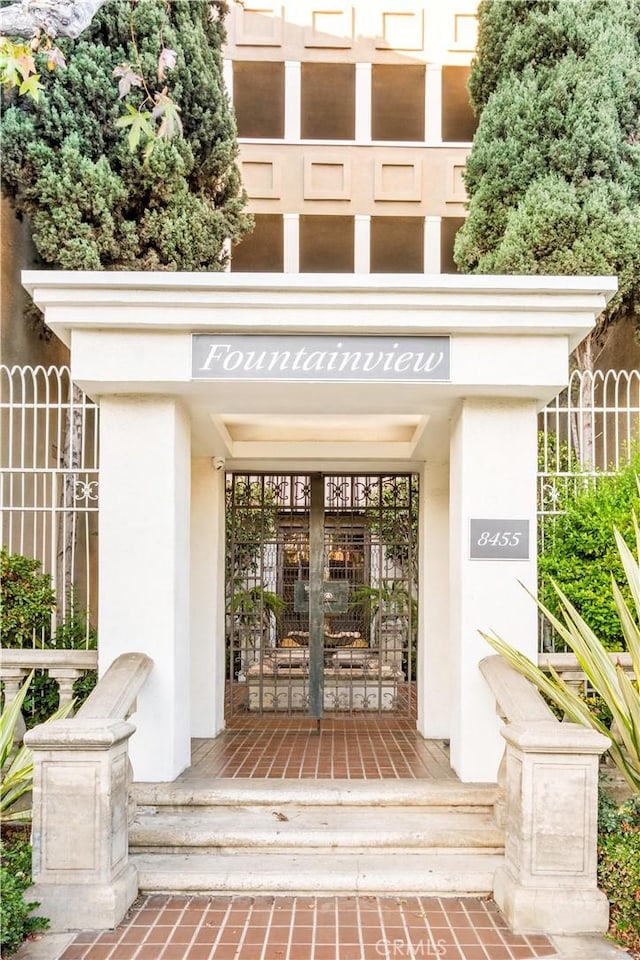 property entrance featuring fence and stucco siding