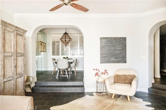 interior space with dark tile patterned flooring, arched walkways, a ceiling fan, and ornamental molding