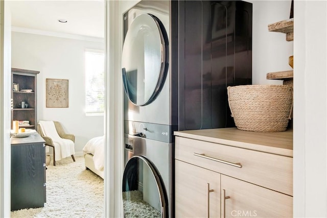 laundry area featuring laundry area, stacked washer / dryer, crown molding, carpet floors, and baseboards