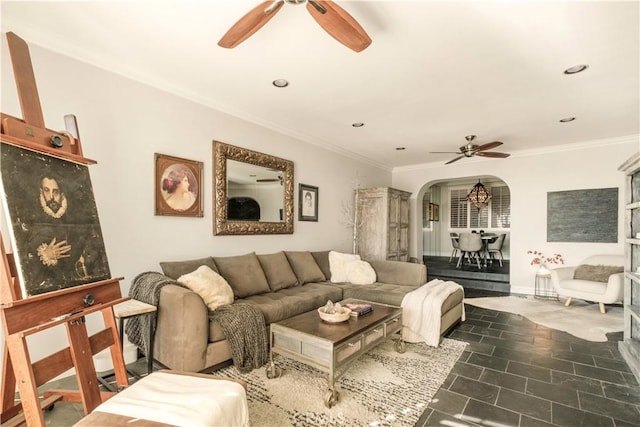 living area with crown molding, a ceiling fan, and arched walkways