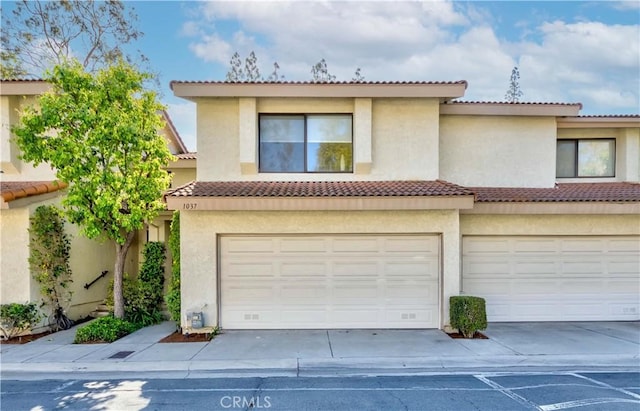 view of front of property with concrete driveway, an attached garage, and stucco siding