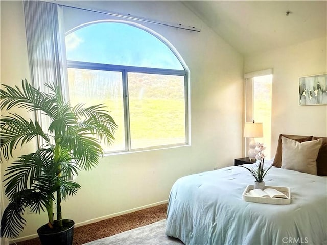 carpeted bedroom featuring baseboards, vaulted ceiling, and multiple windows