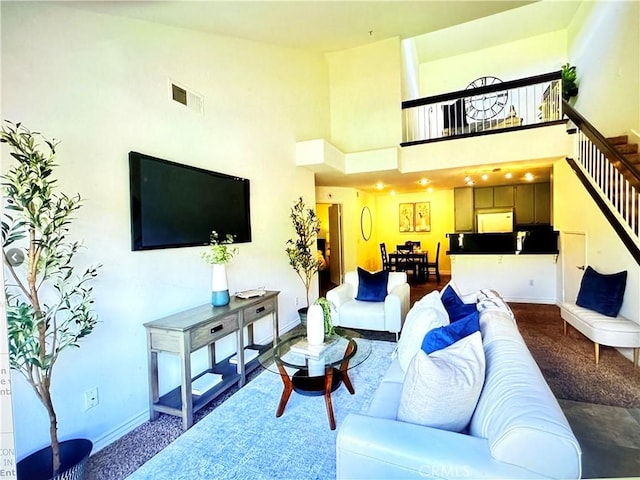 living area featuring visible vents, a towering ceiling, baseboards, stairway, and carpet