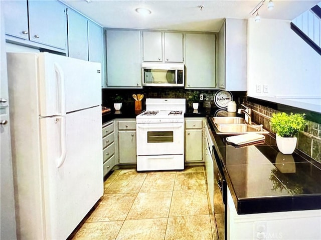 kitchen with dark countertops, a sink, decorative backsplash, and white appliances