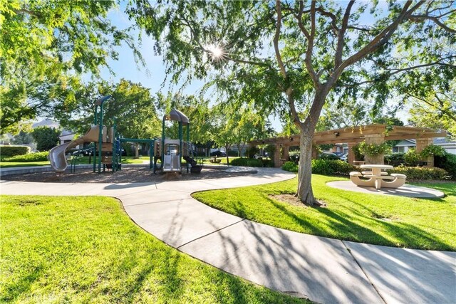 view of property's community with playground community and a yard
