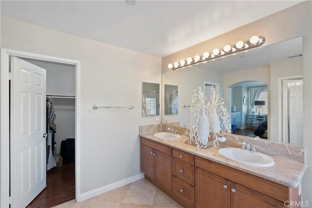 bathroom featuring visible vents, a sink, baseboards, and double vanity