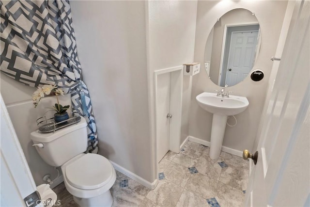 bathroom featuring toilet, baseboards, and a sink