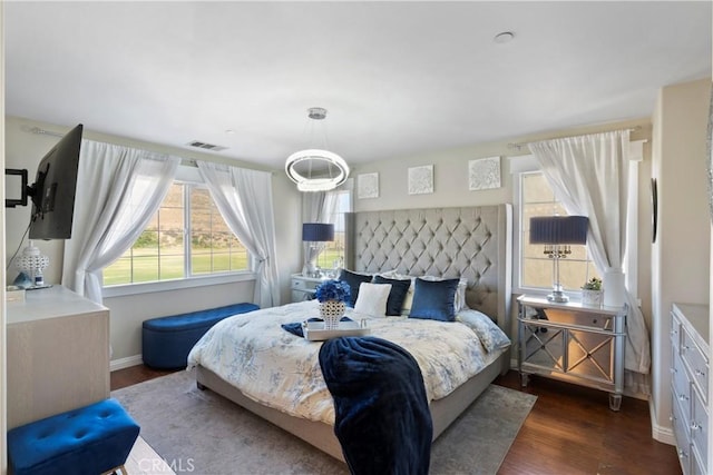 bedroom with visible vents, baseboards, and wood finished floors