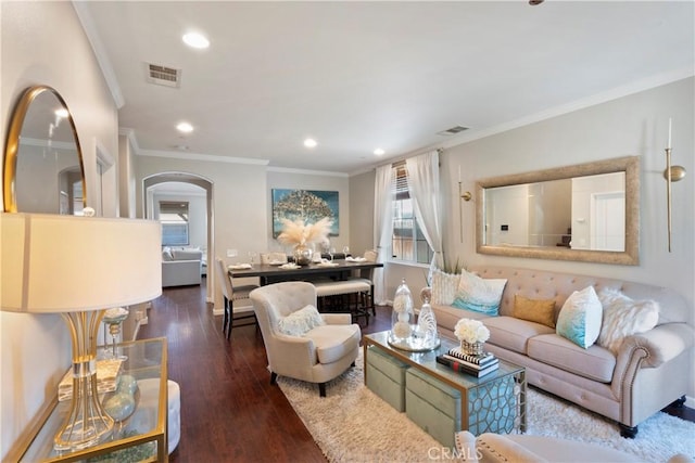 living area with arched walkways, visible vents, ornamental molding, and wood finished floors