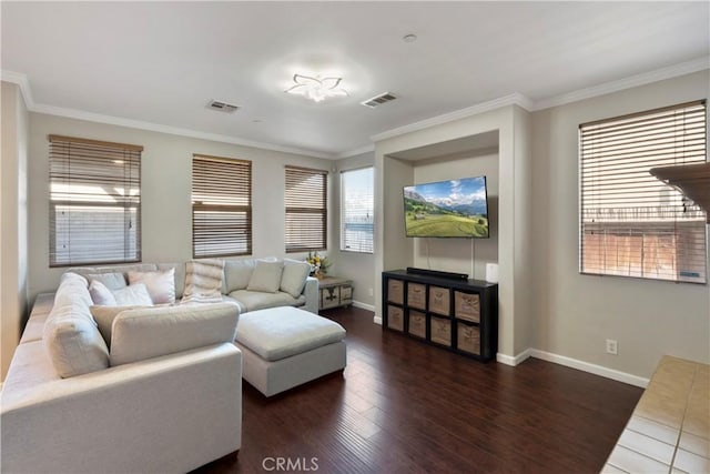 living area with baseboards, ornamental molding, wood finished floors, and visible vents