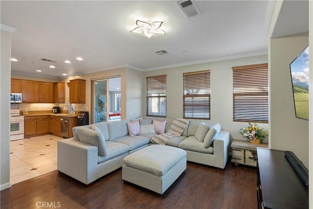 living room featuring ornamental molding, recessed lighting, wood finished floors, and visible vents