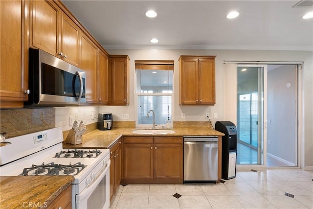 kitchen with a sink, appliances with stainless steel finishes, brown cabinets, and ornamental molding