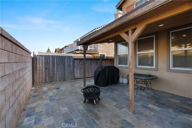 view of patio with area for grilling, a fenced backyard, and an outdoor fire pit