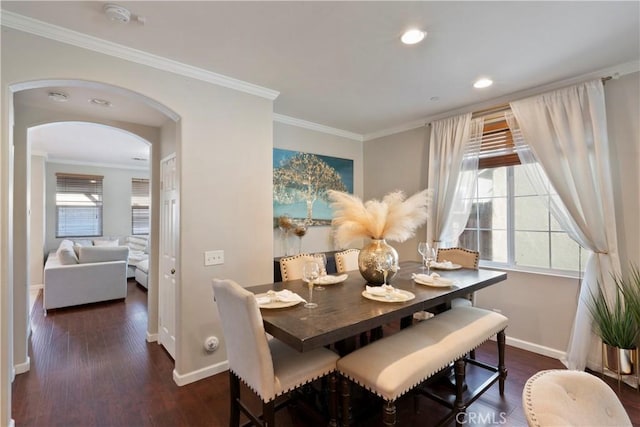 dining space featuring crown molding, arched walkways, wood finished floors, baseboards, and recessed lighting