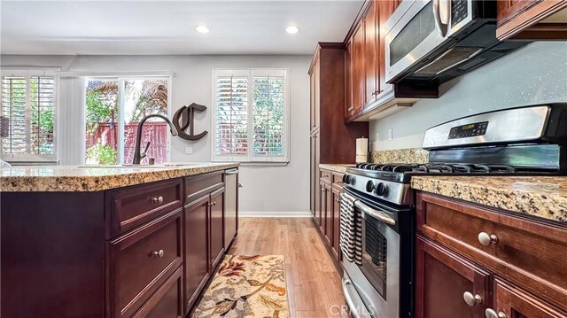 24939 Coral Canyon Rd, Corona, CA 92883 - kitchen with appliances with stainless steel finishes, a sink, light wood finished floors, baseboards, and light stone countertops