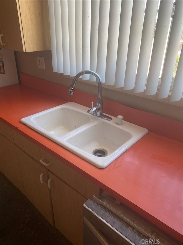 kitchen with a sink, dishwashing machine, and light countertops