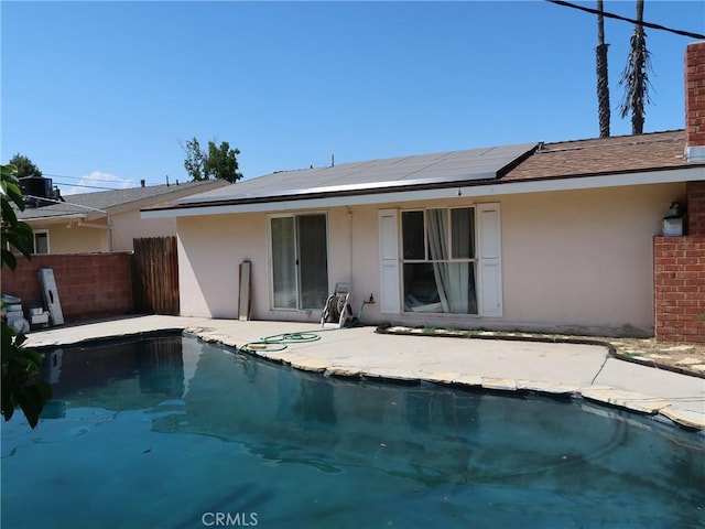 rear view of house featuring an outdoor pool, stucco siding, and solar panels