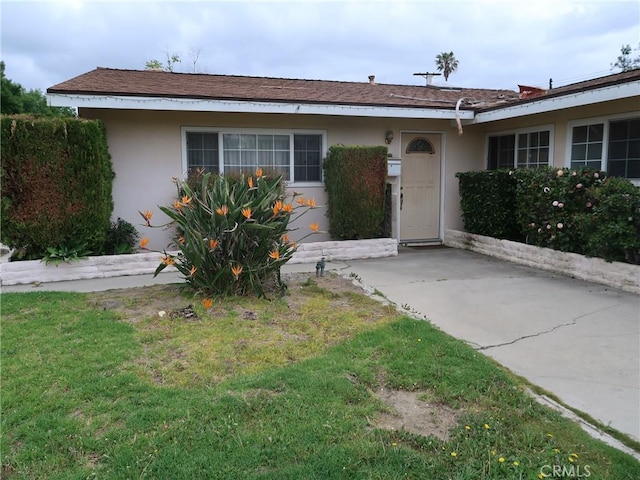 ranch-style home featuring stucco siding and a front yard