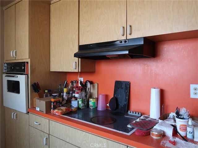 kitchen with under cabinet range hood, light brown cabinets, and white oven