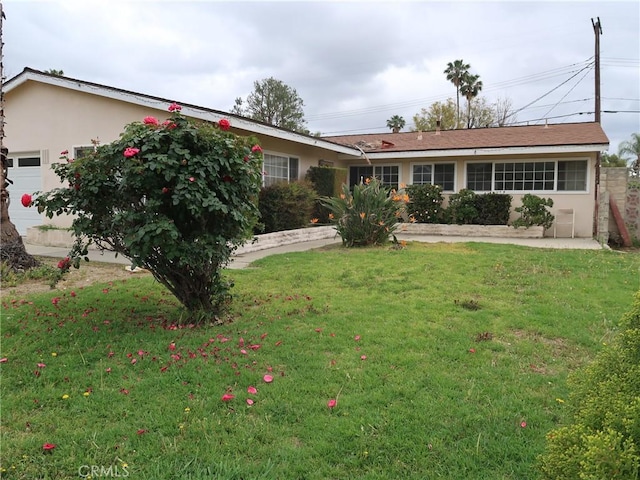 single story home featuring a garage, a front lawn, and stucco siding