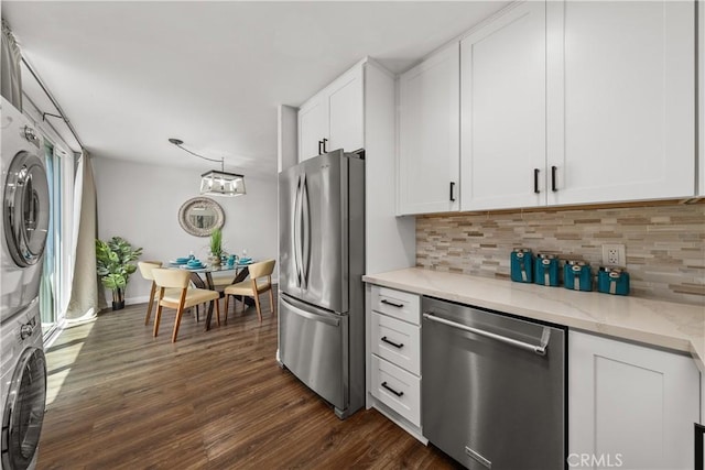 kitchen featuring decorative backsplash, stacked washing maching and dryer, dark wood-type flooring, white cabinets, and appliances with stainless steel finishes