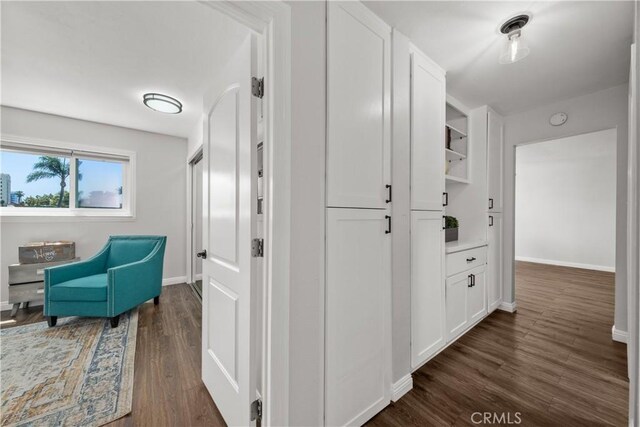 corridor featuring baseboards and dark wood-style floors