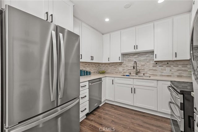 kitchen with dark wood finished floors, light countertops, a sink, stainless steel appliances, and recessed lighting