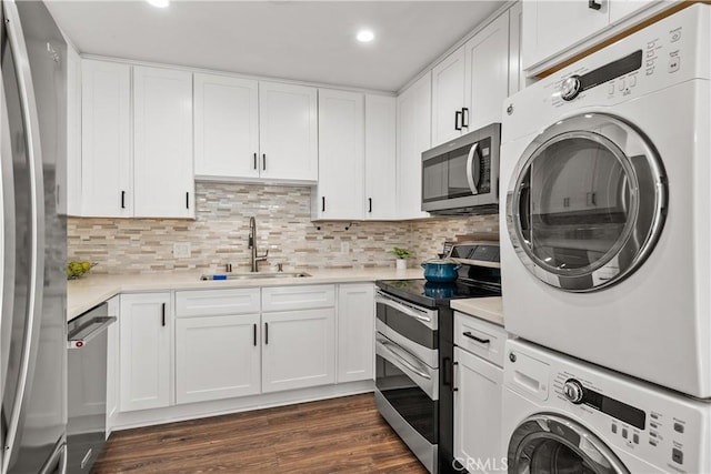 laundry area featuring laundry area, a sink, stacked washing maching and dryer, recessed lighting, and dark wood-type flooring