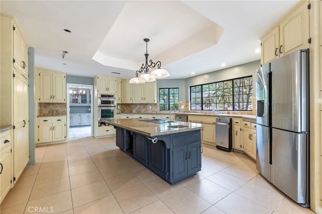 845 N Glendora Ave, Glendora, CA 91741 - kitchen with a center island with sink, a tray ceiling, cream cabinetry, tasteful backsplash, and appliances with stainless steel finishes
