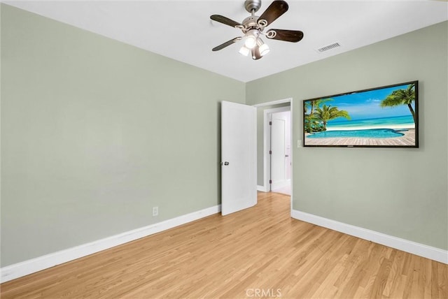 empty room featuring baseboards, light wood finished floors, ceiling fan, and visible vents