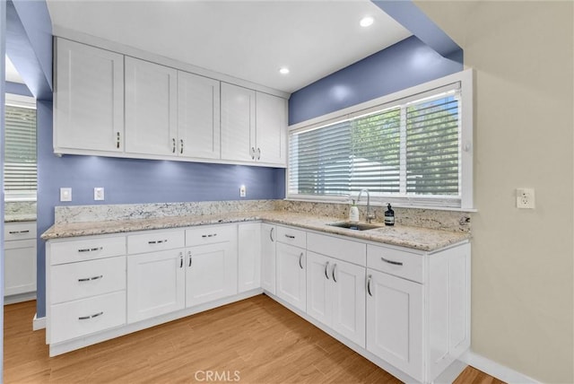 kitchen with a sink, white cabinetry, and light wood-style flooring