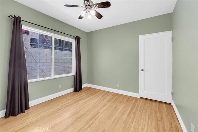 empty room featuring baseboards, ceiling fan, and light wood-type flooring