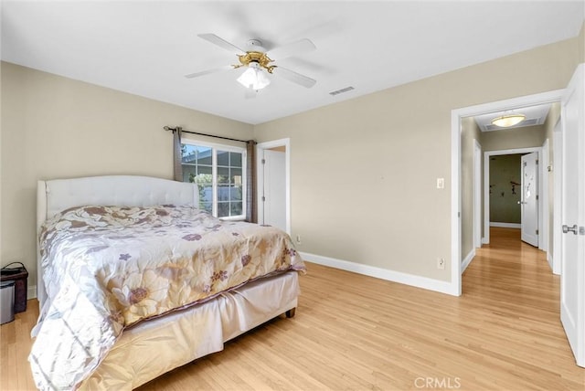 bedroom with baseboards, a ceiling fan, light wood finished floors, and visible vents