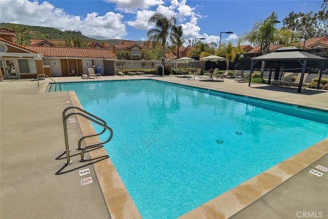pool with a gazebo, fence, a residential view, and a patio area