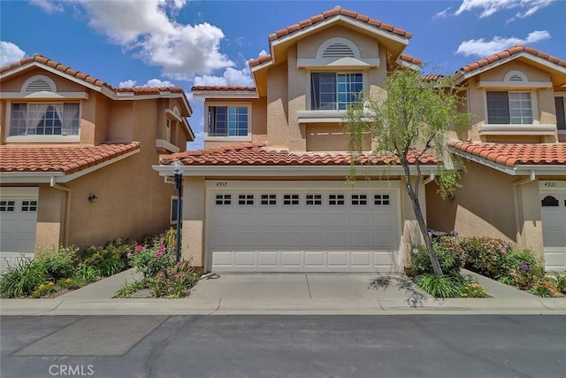 view of front of house featuring a tiled roof, stucco siding, driveway, and a garage