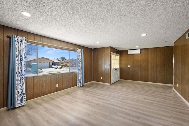 spare room with wooden walls, baseboards, light wood-style flooring, and a wealth of natural light