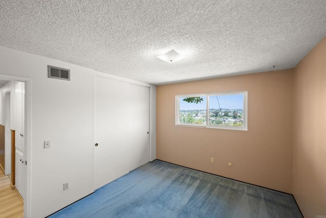 empty room featuring carpet floors, a textured ceiling, and visible vents