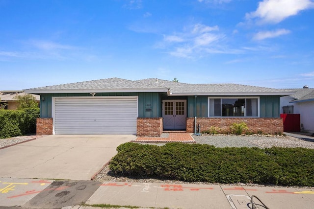 ranch-style house featuring roof with shingles, an attached garage, brick siding, board and batten siding, and concrete driveway