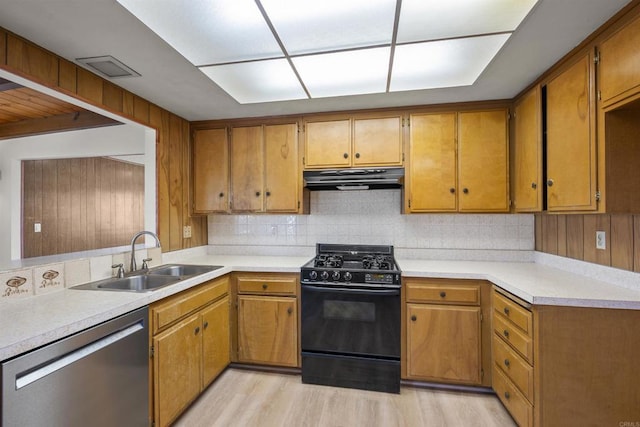 kitchen featuring a sink, dishwasher, black range with gas cooktop, decorative backsplash, and under cabinet range hood