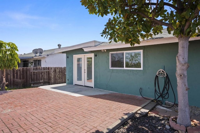 rear view of house with french doors, fence, a patio, and stucco siding