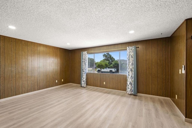 spare room with wooden walls, a textured ceiling, recessed lighting, and wood finished floors
