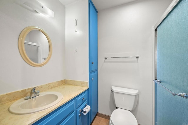 bathroom featuring an enclosed shower, toilet, wood finished floors, and vanity