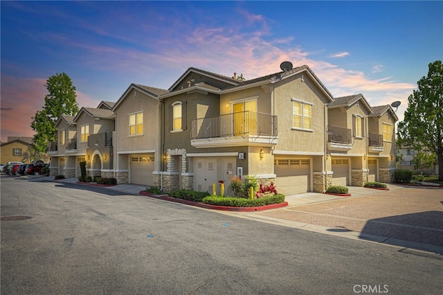 7353 W Ellena W Unit 83, Rancho Cucamonga, CA 91730 - townhome / multi-family property featuring stone siding, a garage, a balcony, stucco siding, and driveway