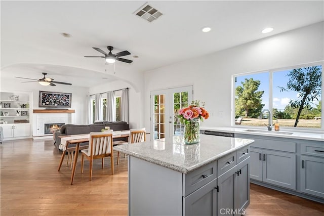 kitchen featuring a sink, visible vents, a ceiling fan, a kitchen island, and gray cabinetry